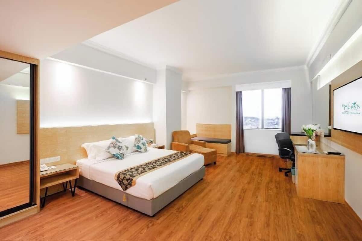 A hotel room with a bed, desk, chair, and a large window.