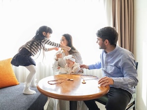 A family of four around a round wooden table with a stethoscope on it, in a room with a window and curtains. - Grand Mercure Sapporo Odori Park (Sapporo)