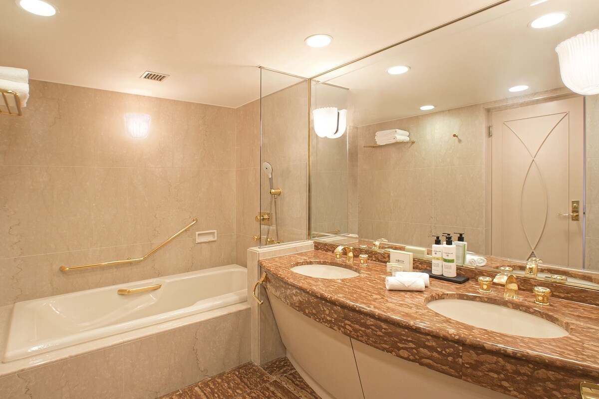 A modern bathroom with a bathtub, two sinks, and a large mirror.