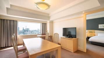 A hotel room with a city view, a dining table, a TV, and a bed.