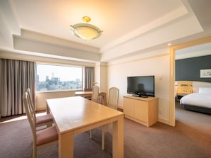 Una camera d'hotel con vista sulla città, un tavolo da pranzo, una TV e un letto.