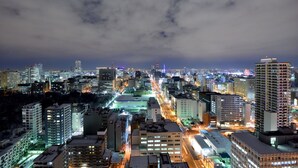 Une vue nocturne d’une ville, avec ses gratte-ciel, ses rues illuminées et un ciel nuageux.