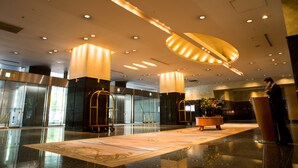 Eine geräumige Lobby mit poliertem Boden, einem großen zentralen Tisch mit Blumenvase und einem Rednerpult.
