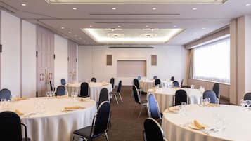 A conference room with round tables, chairs, and a projector screen.