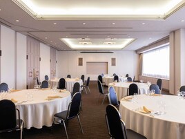 A conference room with round tables, chairs, and a projector screen.