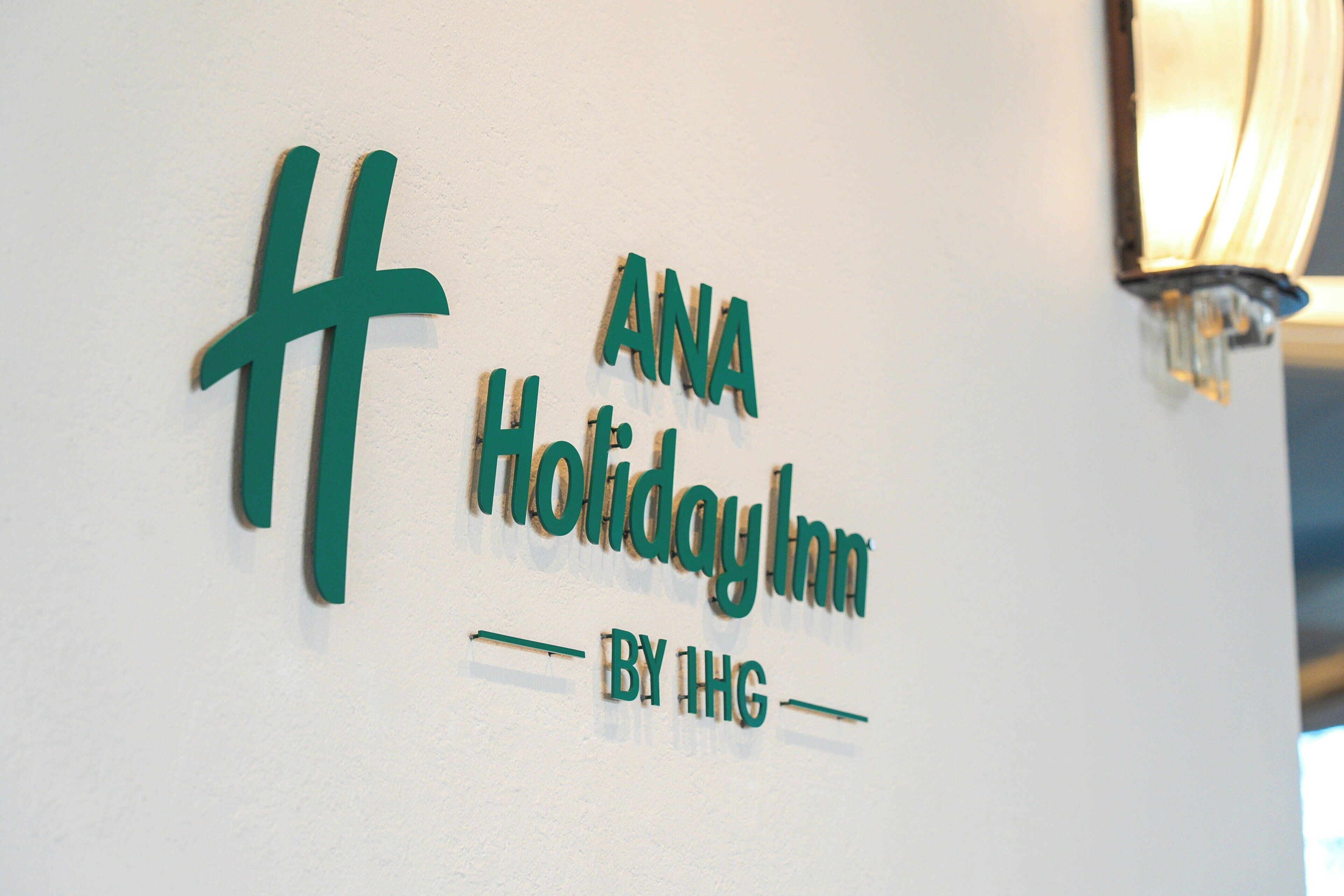 A wall sign for ANA Holiday Inn by IHG with a simple design.