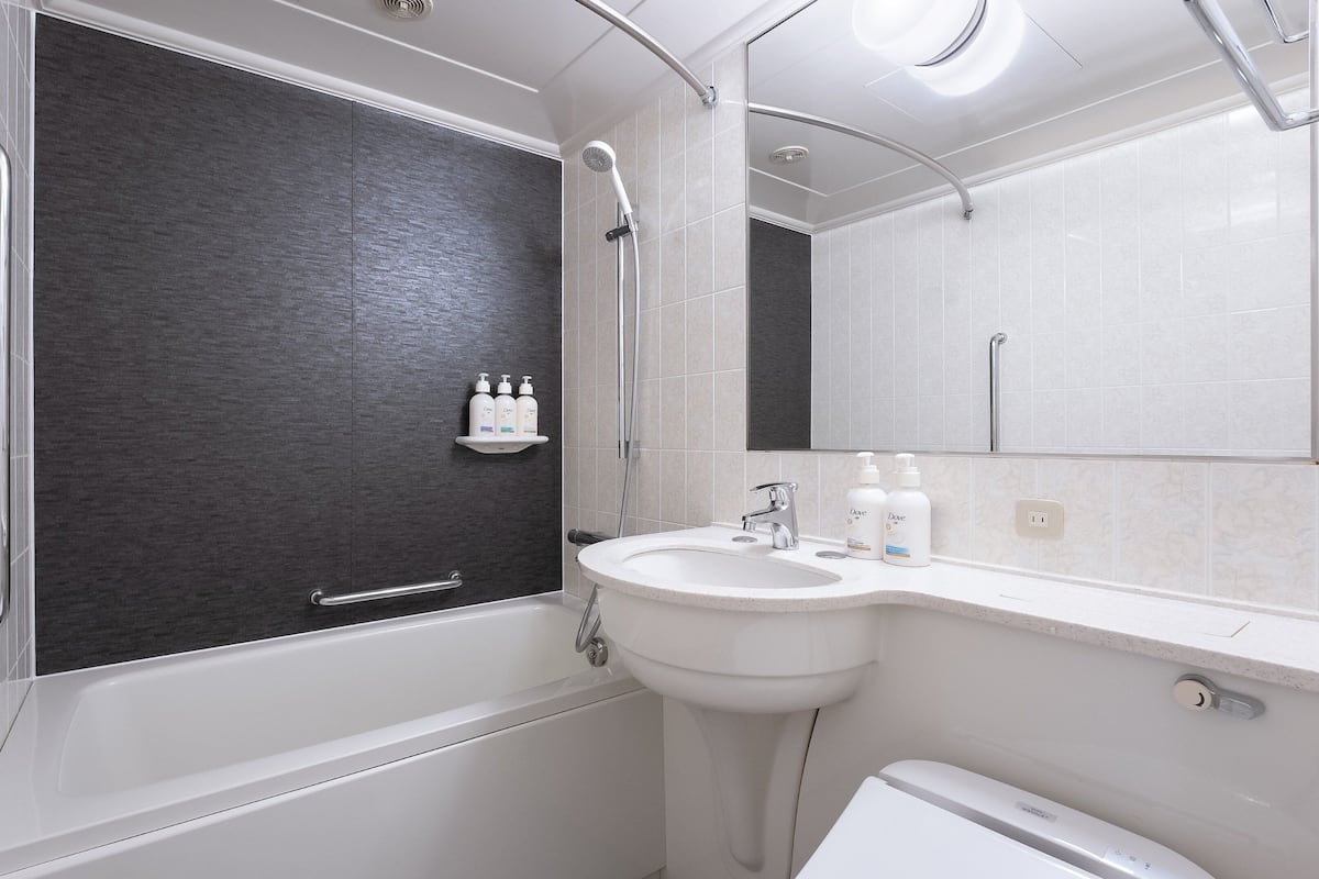 Un baño moderno con bañera, lavabo e inodoro. Hay dos jabones Dove sobre el lavabo.