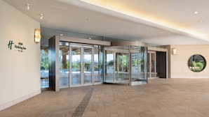 A modern hotel entrance with glass doors, a visible outdoor area, and a circular window. - ANA Holiday Inn Kobe Sanda by IHG (Sanda)
