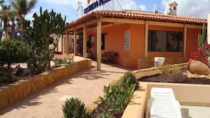 Un hotel con tejado de baldosas, mobiliario exterior y cactus.