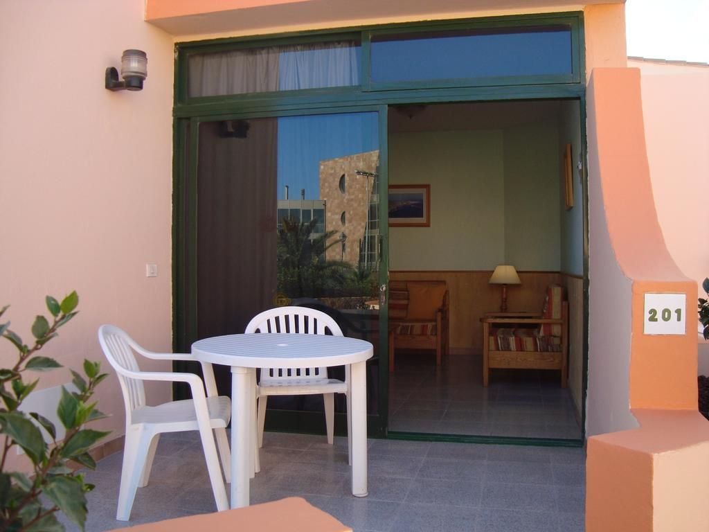 A room with a sliding glass door leading to a balcony, a small round table with two chairs, and a sofa.