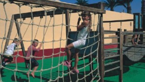 A playground with a netted climbing structure and a slide. - Bungalows Castillo Playa (Antigua)