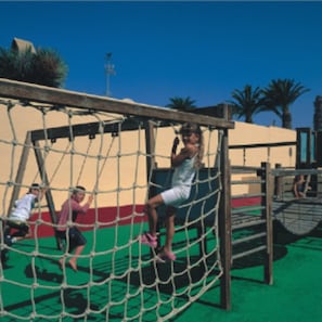 Un’area giochi con una struttura di arrampicata recintata e uno scivolo.
