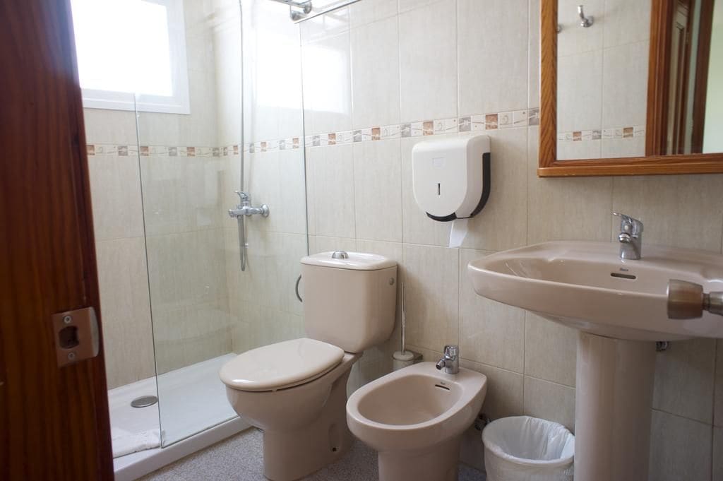 Une salle de bain équipée de toilettes, d’un bidet, d’un lavabo et d’un distributeur de savon liquide.