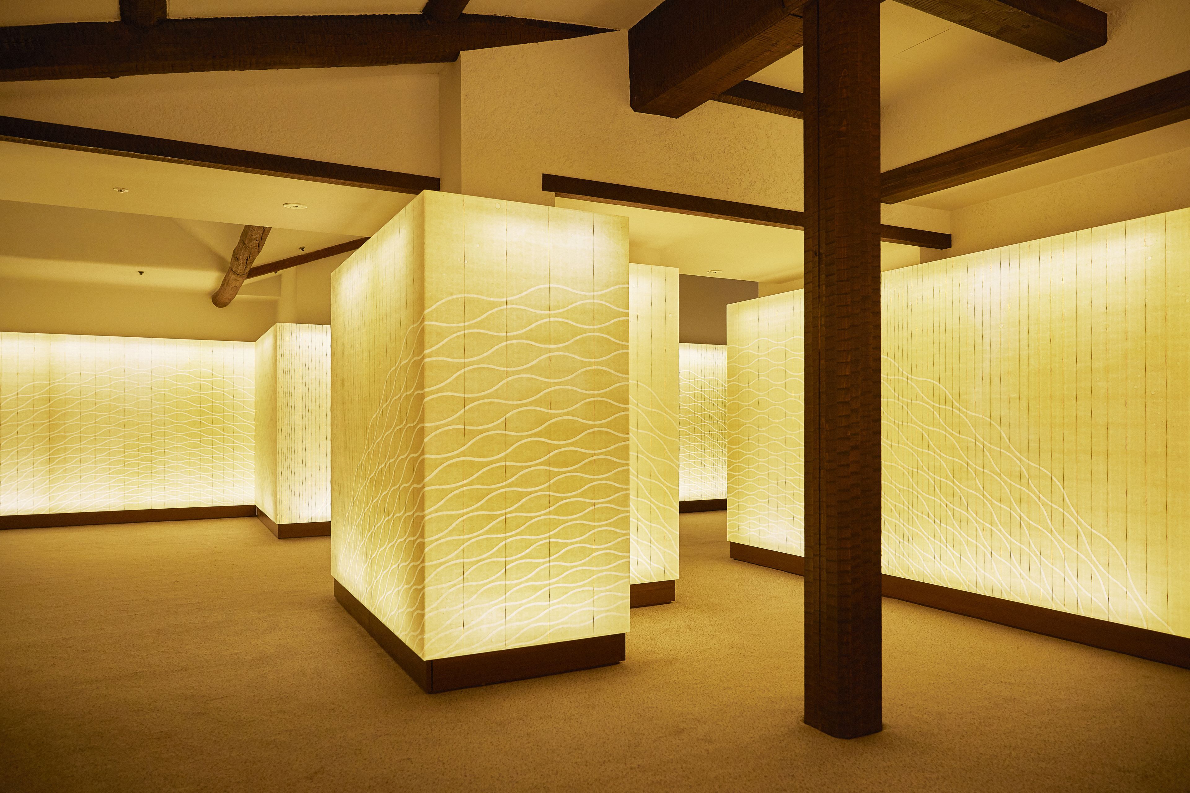 A hotel lobby with a modern design, featuring a patterned wall and wooden beams on the ceiling.