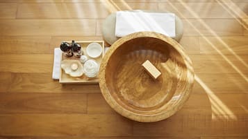 A wooden floor with a wooden bowl and a tray of toiletries.