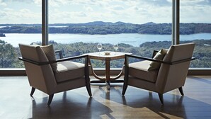A room with two chairs and a table, large windows with a view of a lake and mountains. - Shima Kanko Hotel The Bay Suites (Shima)