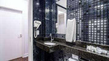 A bathroom with a black tiled wall, a white sink, and a towel hanging on the wall.
