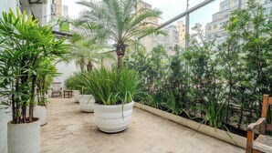 Un patio con plantas en macetas, un banco y vistas a edificios.