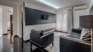 Una sala de estar moderna con un televisor de pantalla plana grande montado en la pared, un sofá de cuero negro y una mesa de centro.