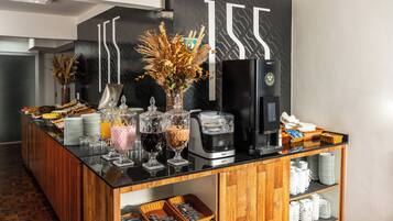 A buffet setup with various food items, beverages, and a coffee machine.