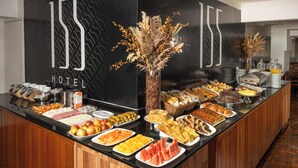Un mostrador de buffet con una variedad de alimentos, como frutas, pasteles y pan, en un entorno hotelero.
