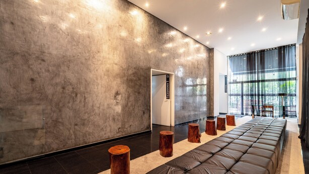 Un interior moderno con un amplio sofá de cuero, taburetes de madera y una puerta de cristal.