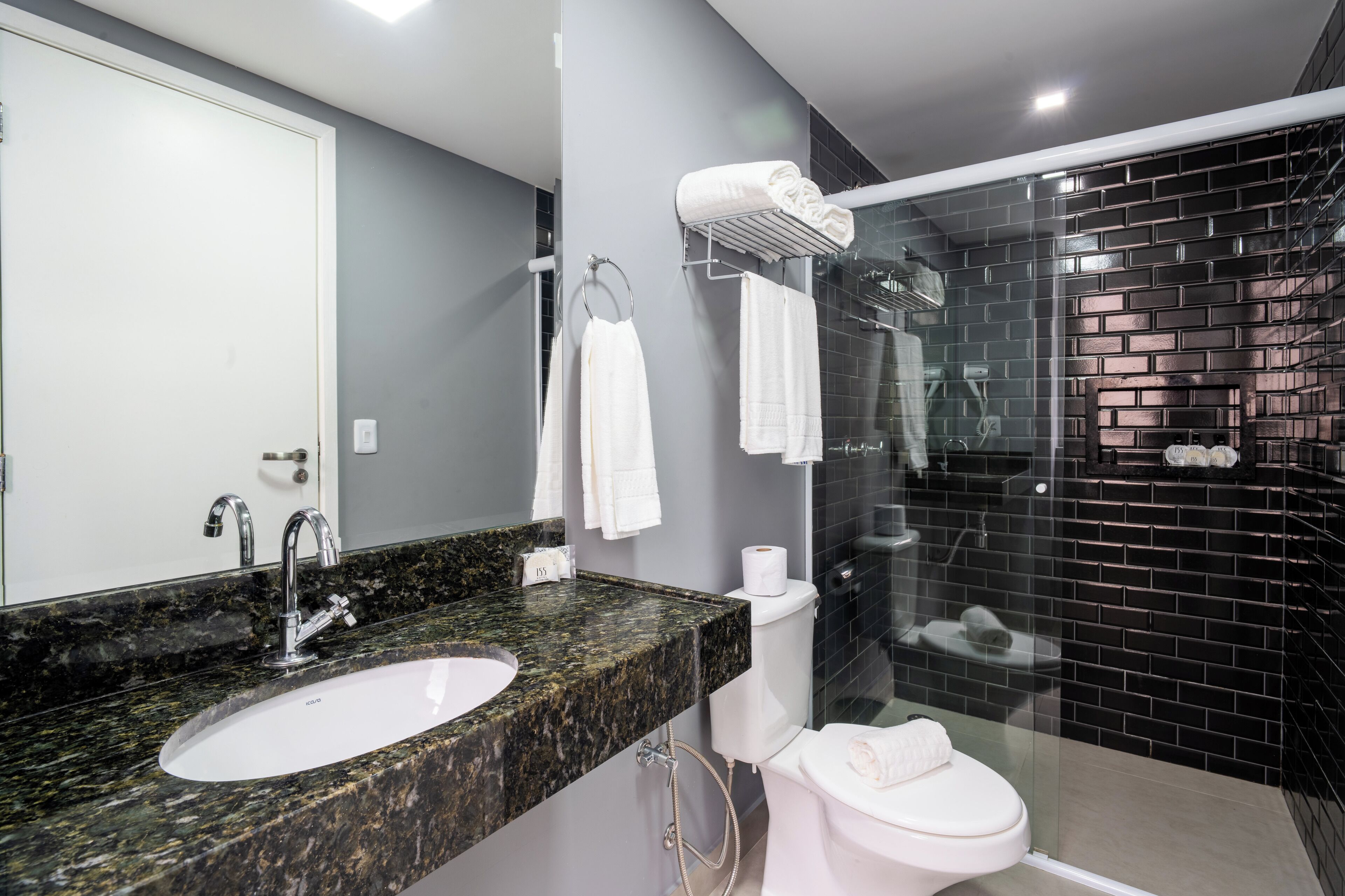 Un baño moderno con lavamanos de granito, inodoro y ducha con mampara de vidrio.