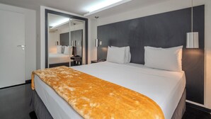 Una habitación de hotel moderna con una cama grande, una pared de acento oscura y un espejo que refleja la habitación.