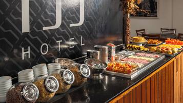A buffet with various food items and containers, including fruits, vegetables, and cereals, in front of a hotel sign.