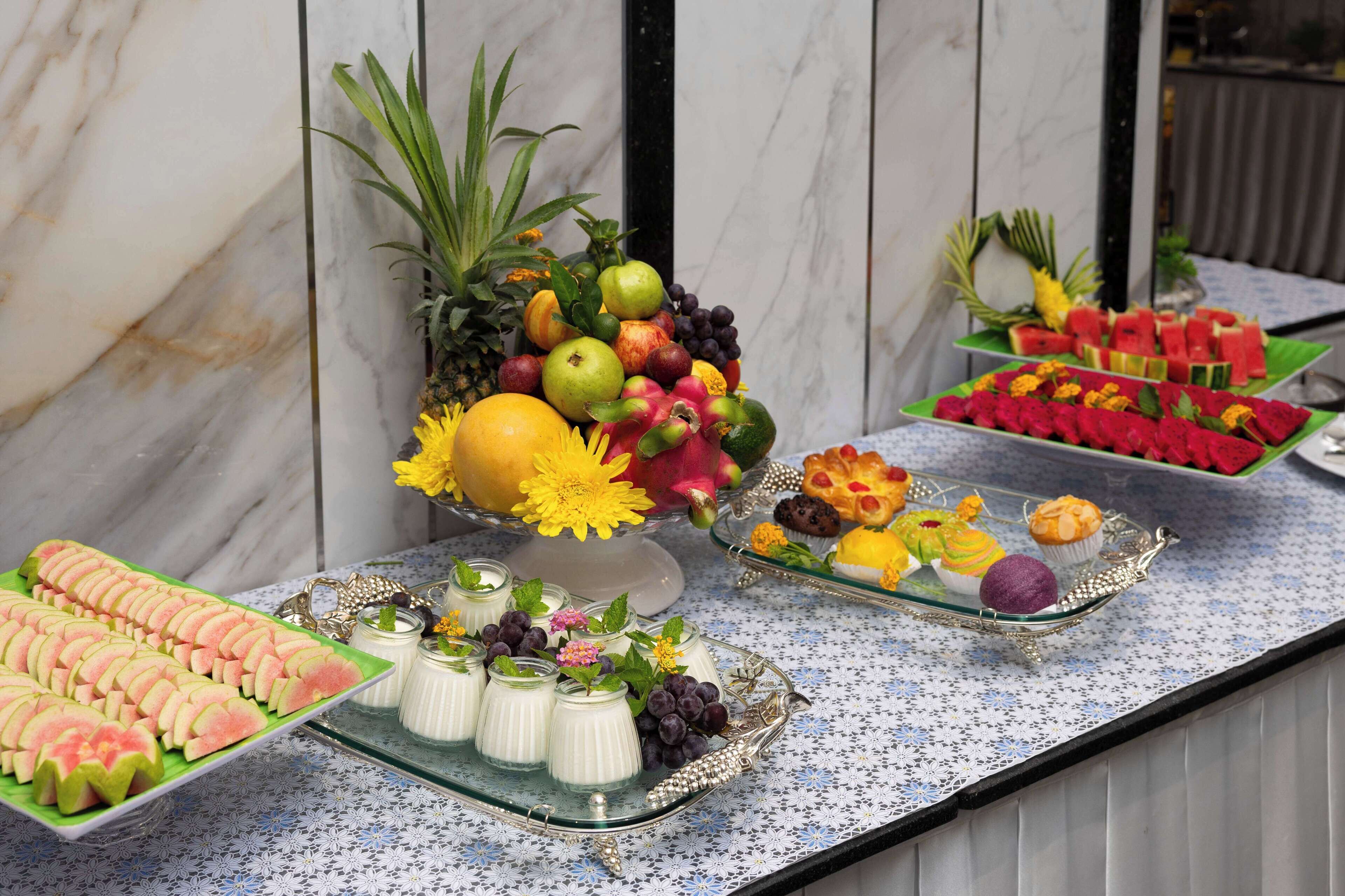 A buffet table with various fruits, pastries, and desserts.