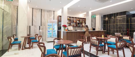 Un vestíbulo de hotel moderno con suelo de mármol, mobiliario de madera, zona de bar y mostrador refrigerado.