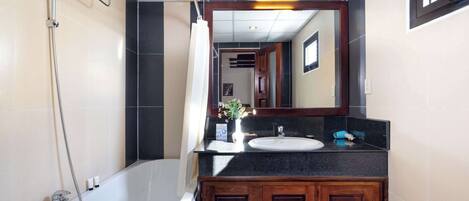 Un baño moderno con bañera, ducha, lavabo y tocador con armarios.