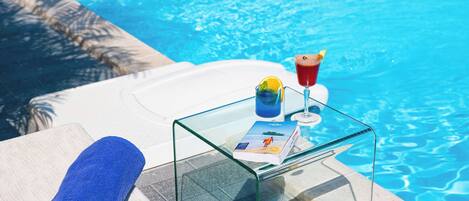 Ett glasbord med en handduk och ett glas stående bredvid en pool.