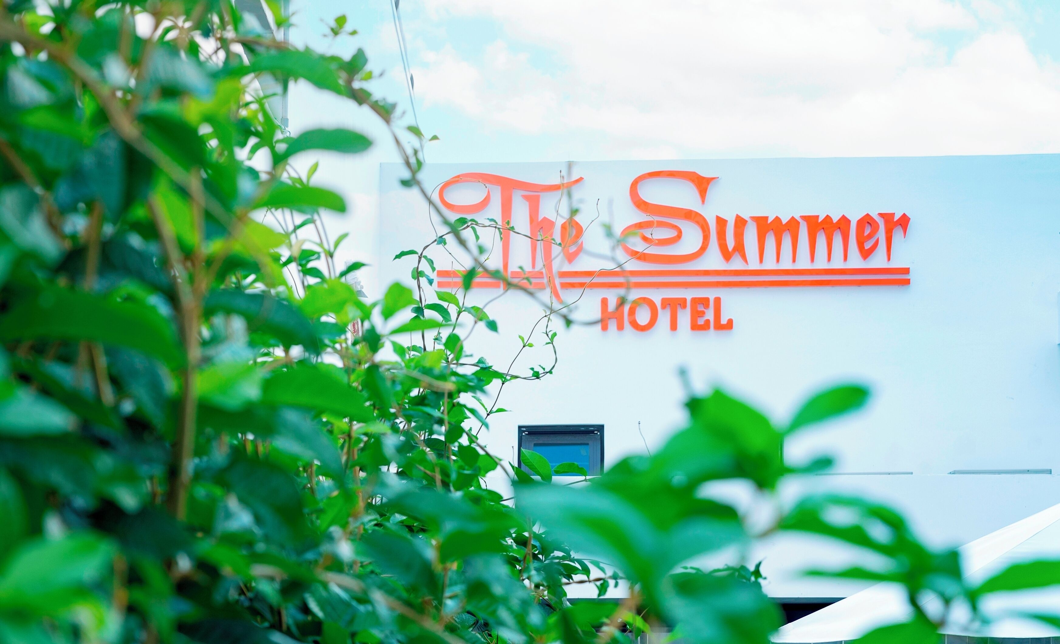 Un letrero de hotel con el nombre 'The Summer Hotel' en letras anaranjadas y negritas.