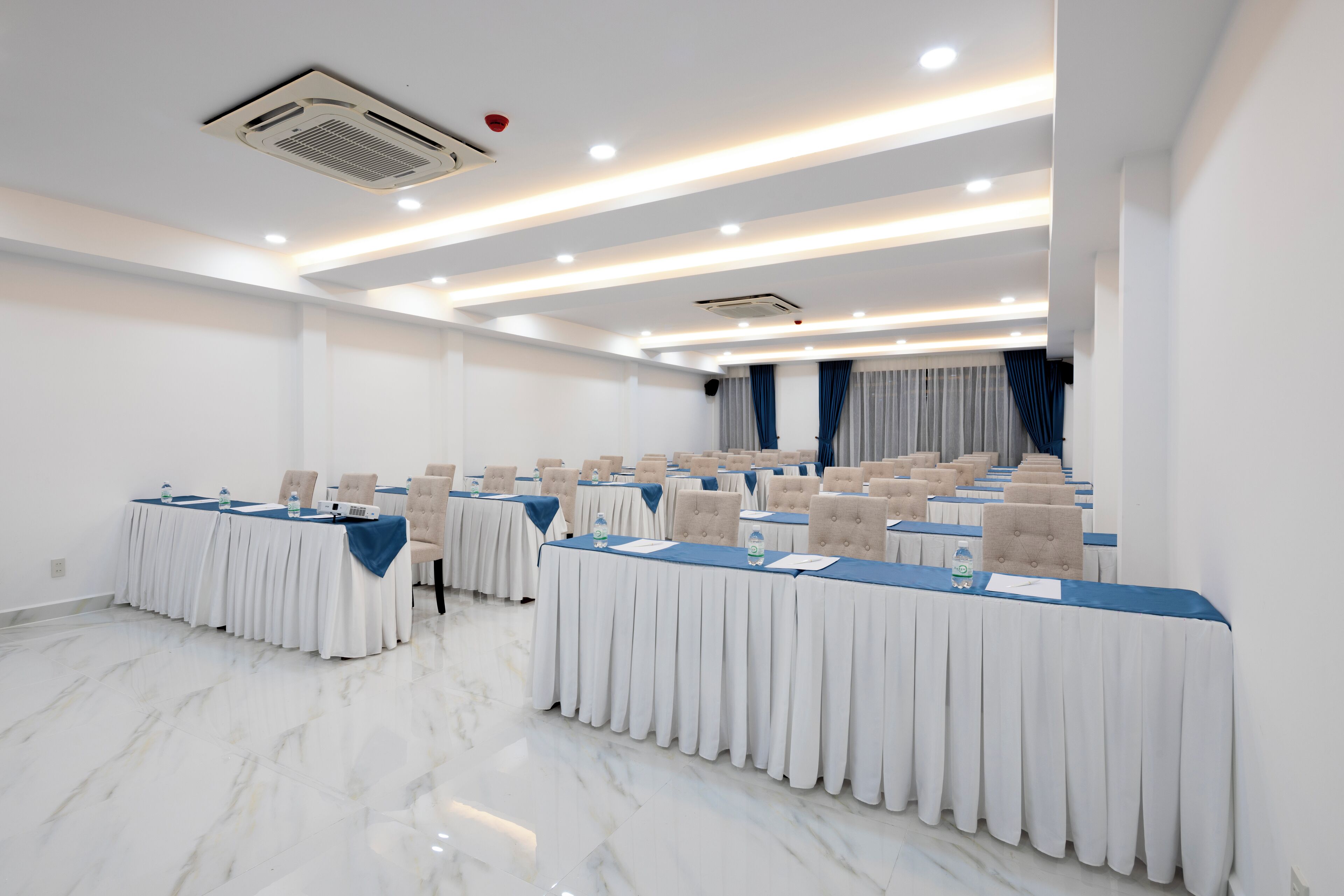 A conference room with multiple tables, chairs, and a marble floor.