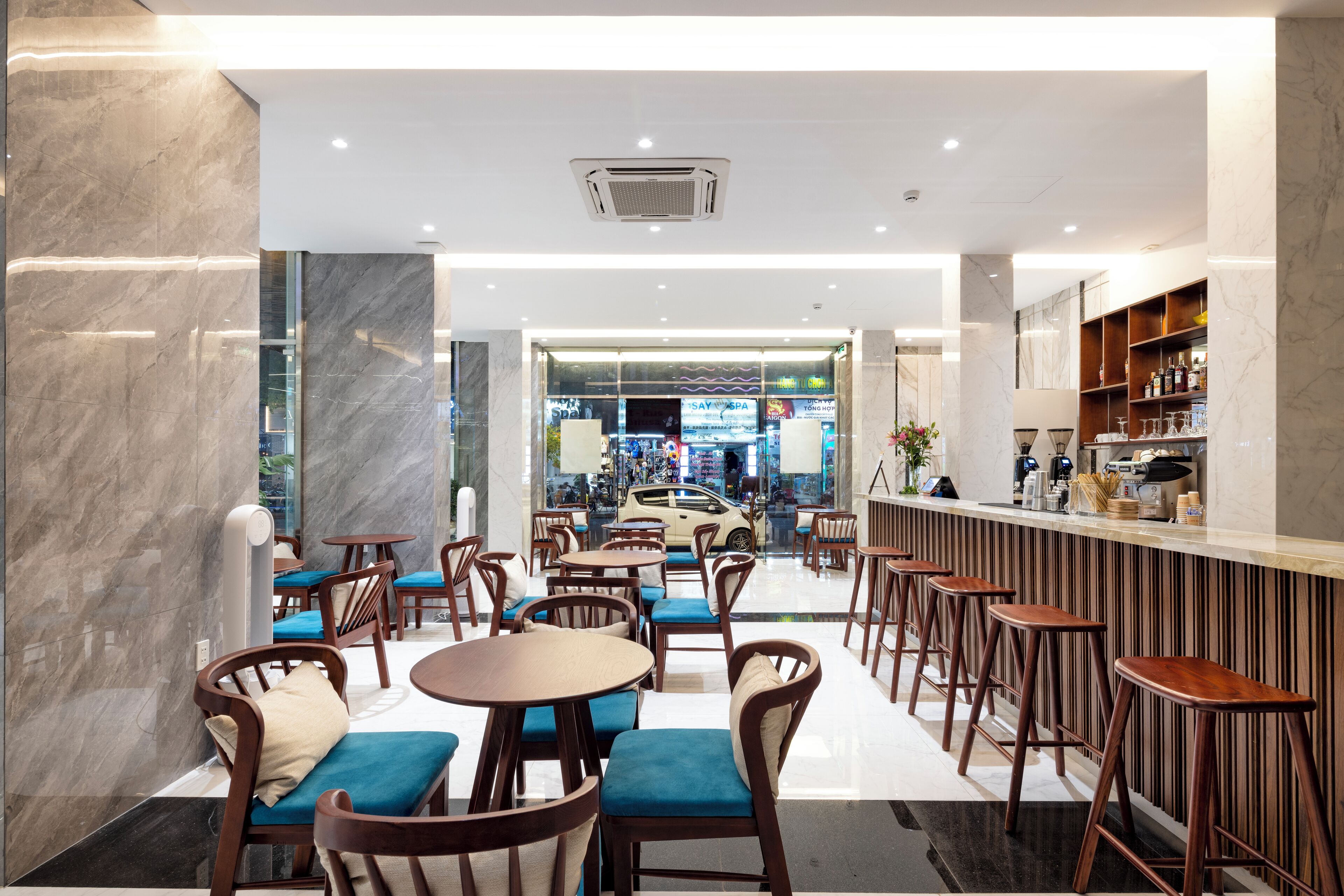 A modern cafe with marble walls, wooden furniture, and a bar area.