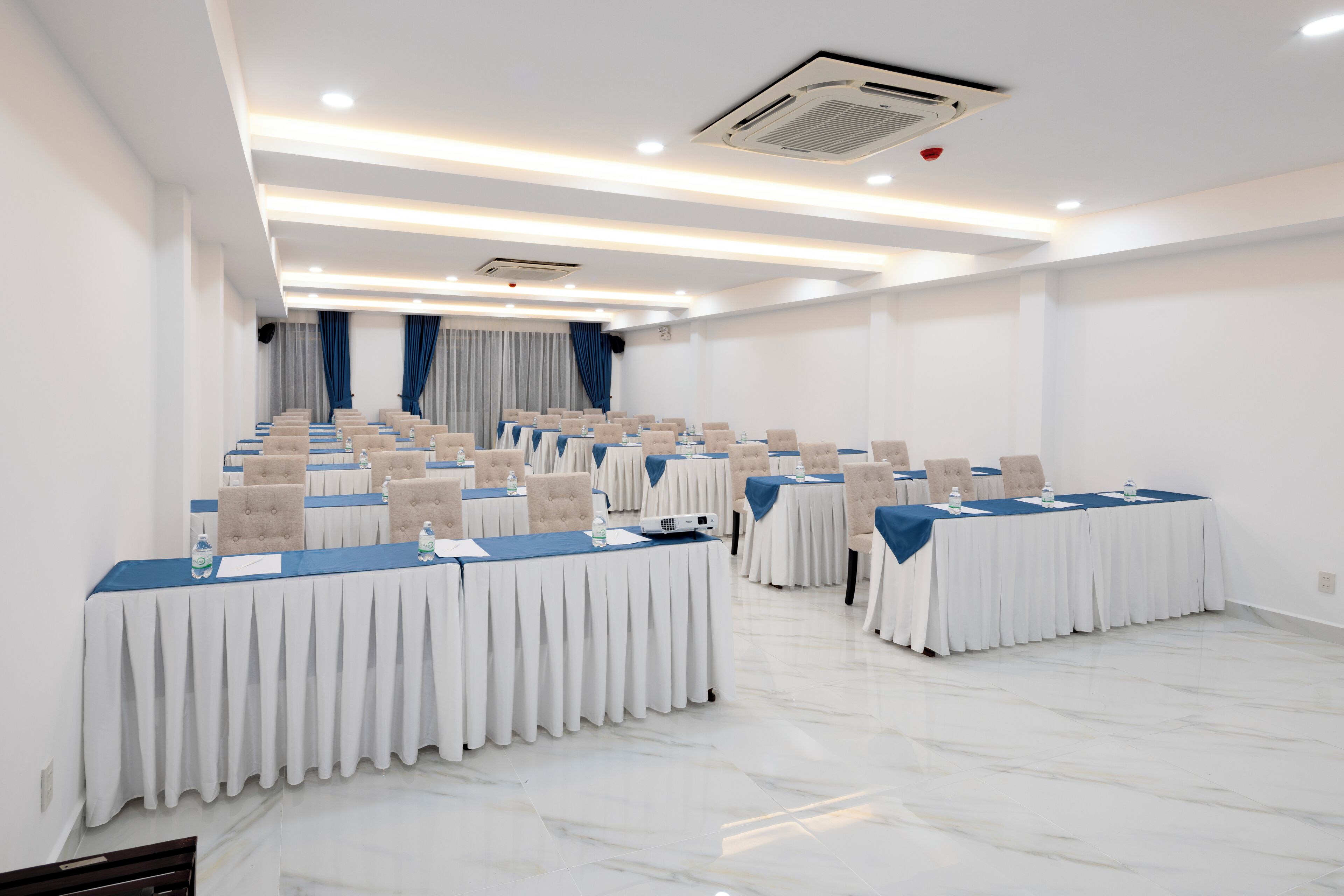 Une salle de conférence avec des rangées de tables, des chaises et une estrade.