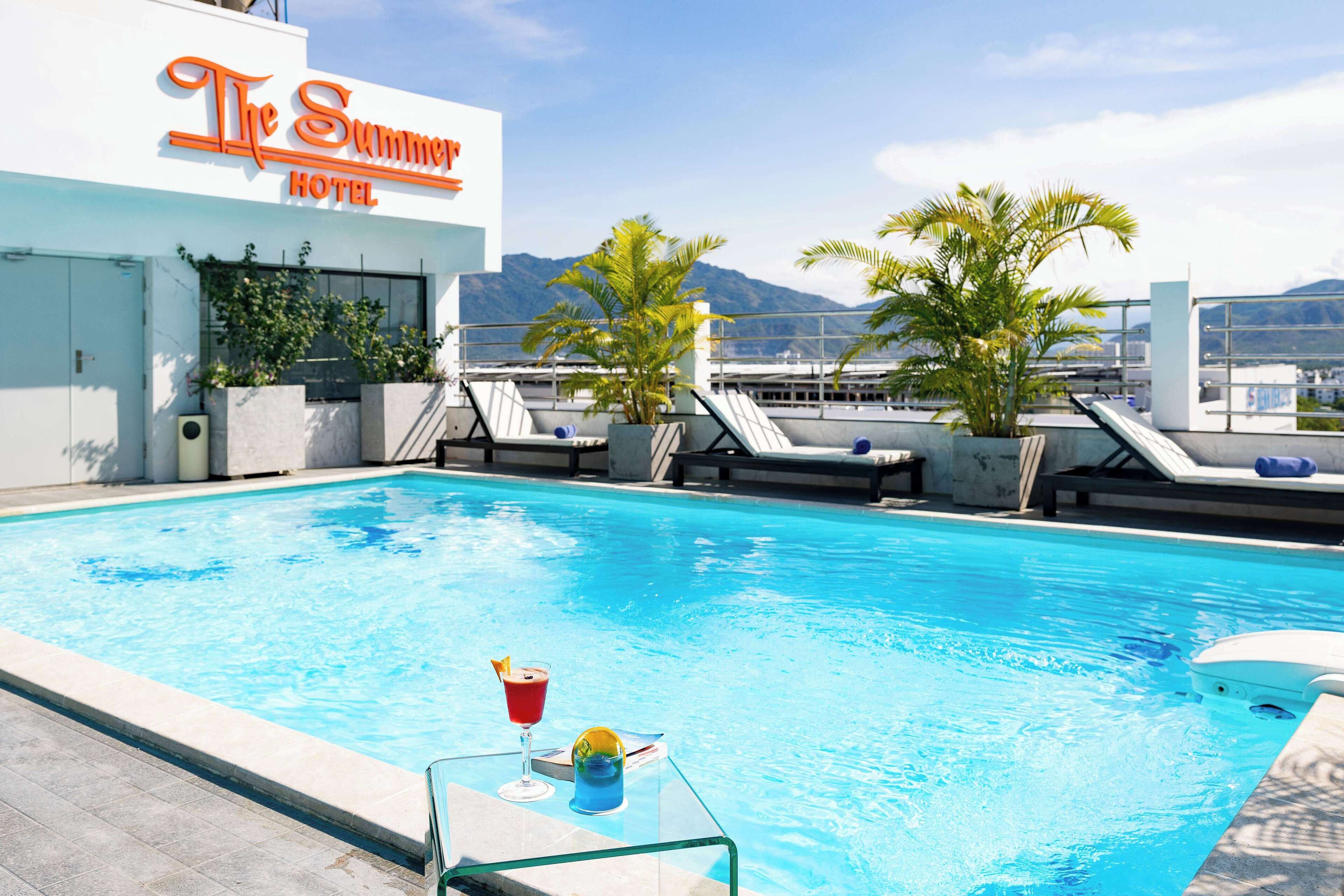A rooftop pool area with lounge chairs and a sign for 'The Summer Hotel'.