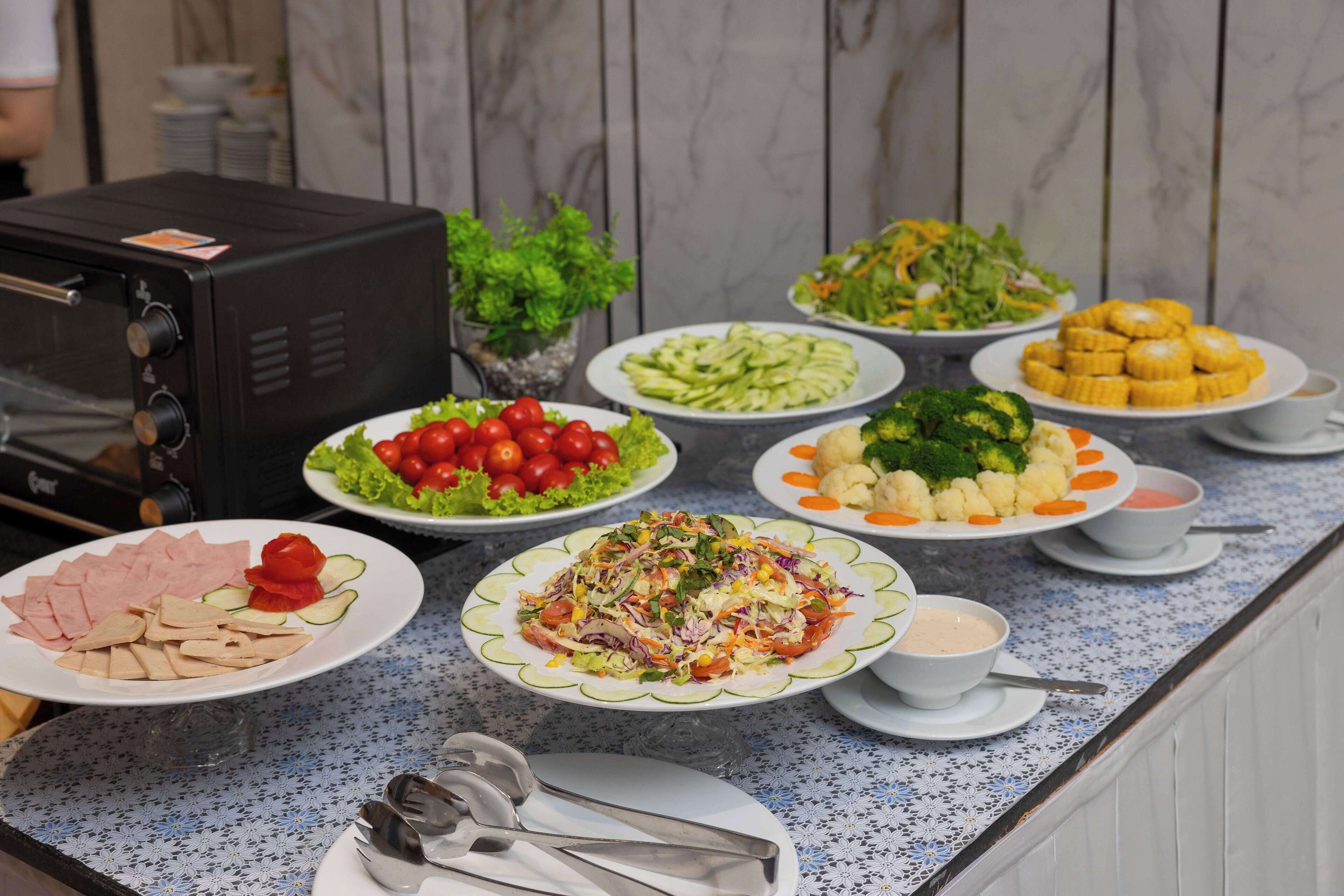 Une table de buffet proposant divers plats, notamment des salades, des légumes et de la viande.
