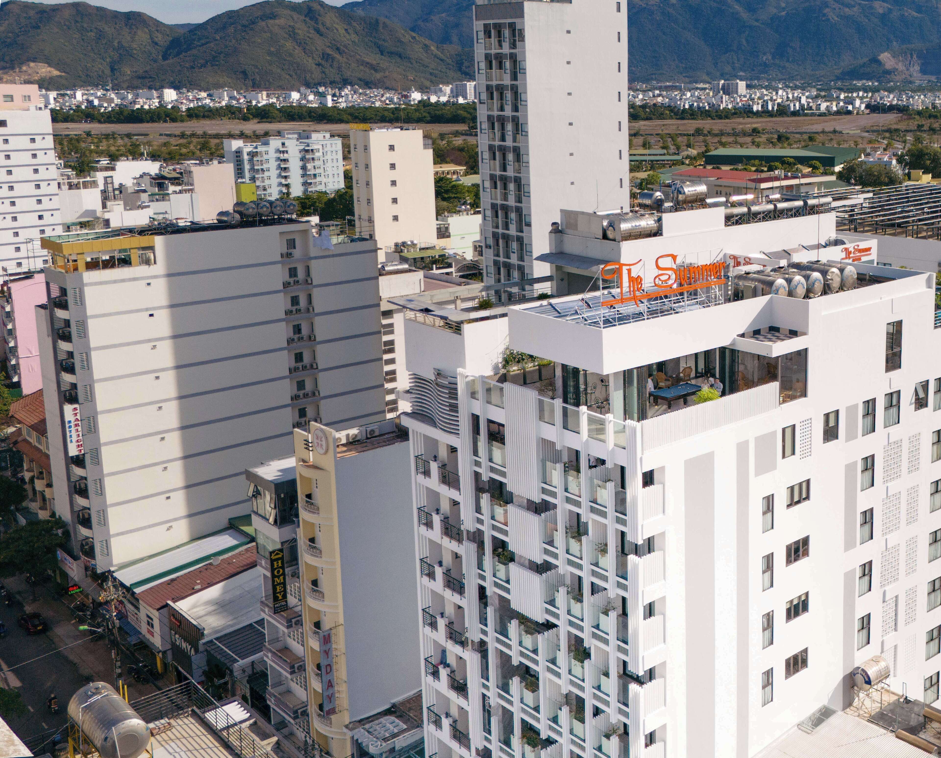 A modern hotel with multiple floors, balconies, and a rooftop bar named "The Summer".