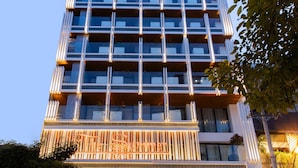 A modern hotel with a glass facade, outdoor seating, and potted plants. - The Summer Hotel (Nha Trang)