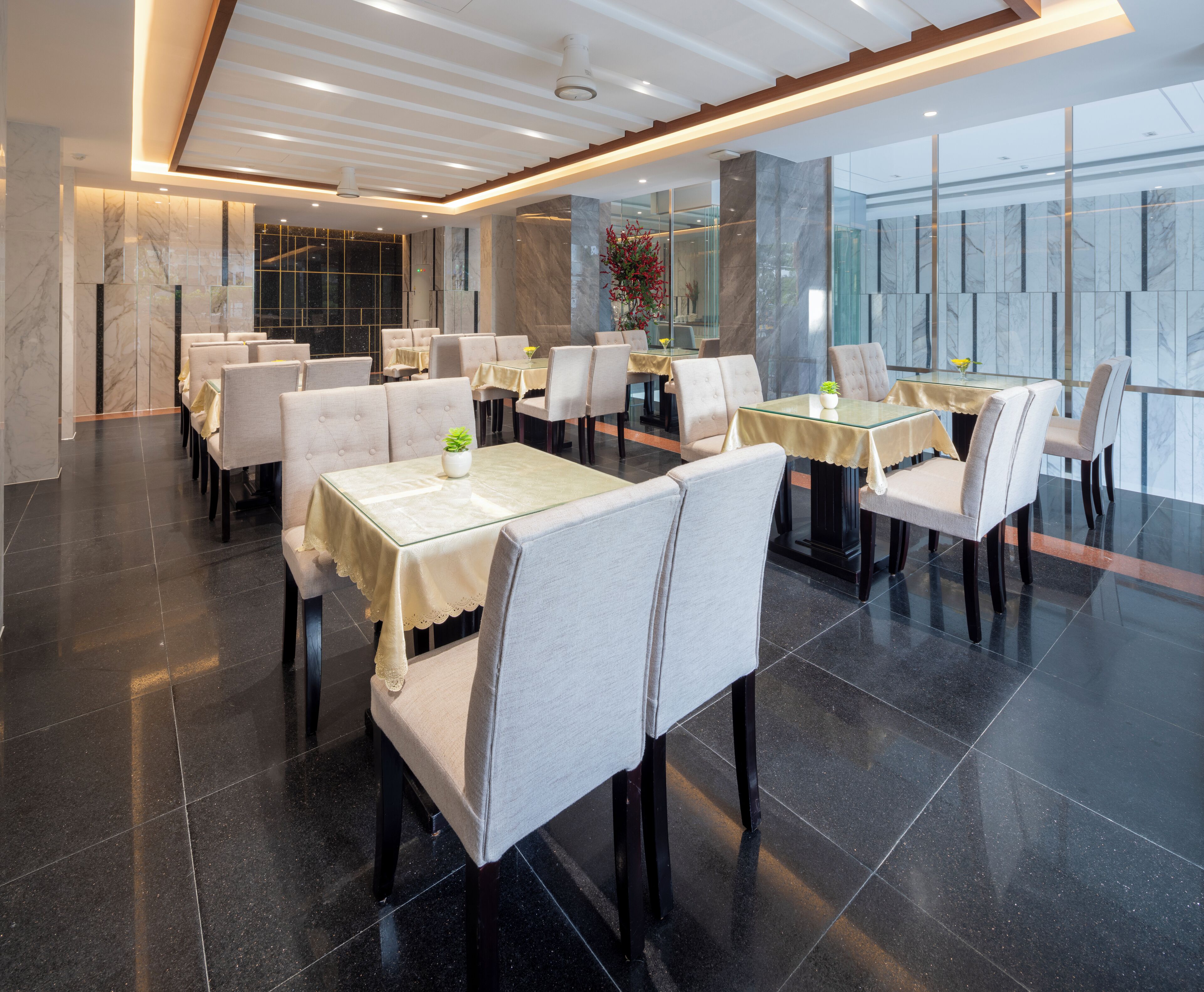 A modern restaurant with a clean, minimalist design, featuring a series of tables and chairs arranged in a spacious layout.