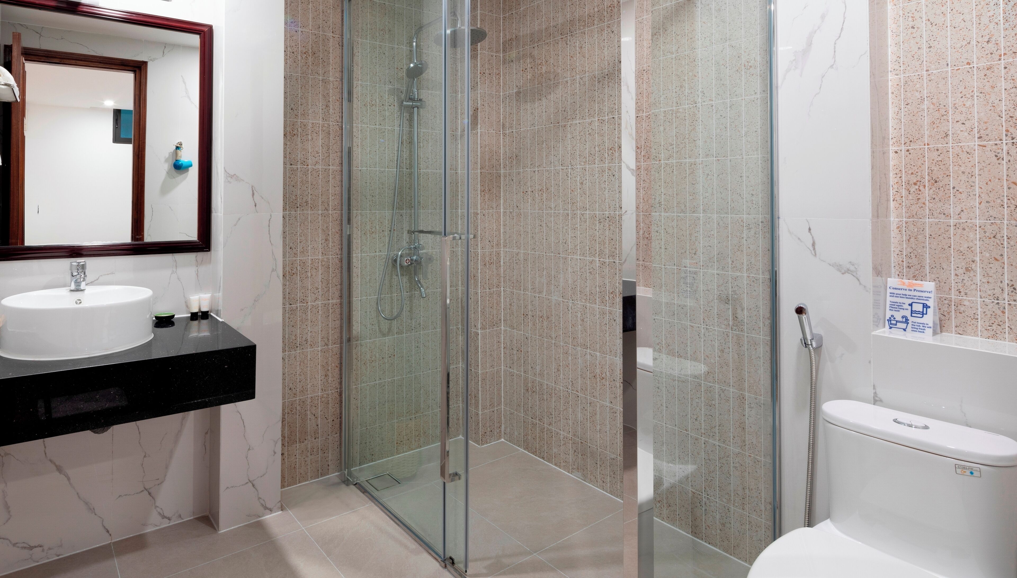 Une salle de bain moderne avec une douche à parois de verre, un lavabo doté d’un plan de travail en marbre et des toilettes.