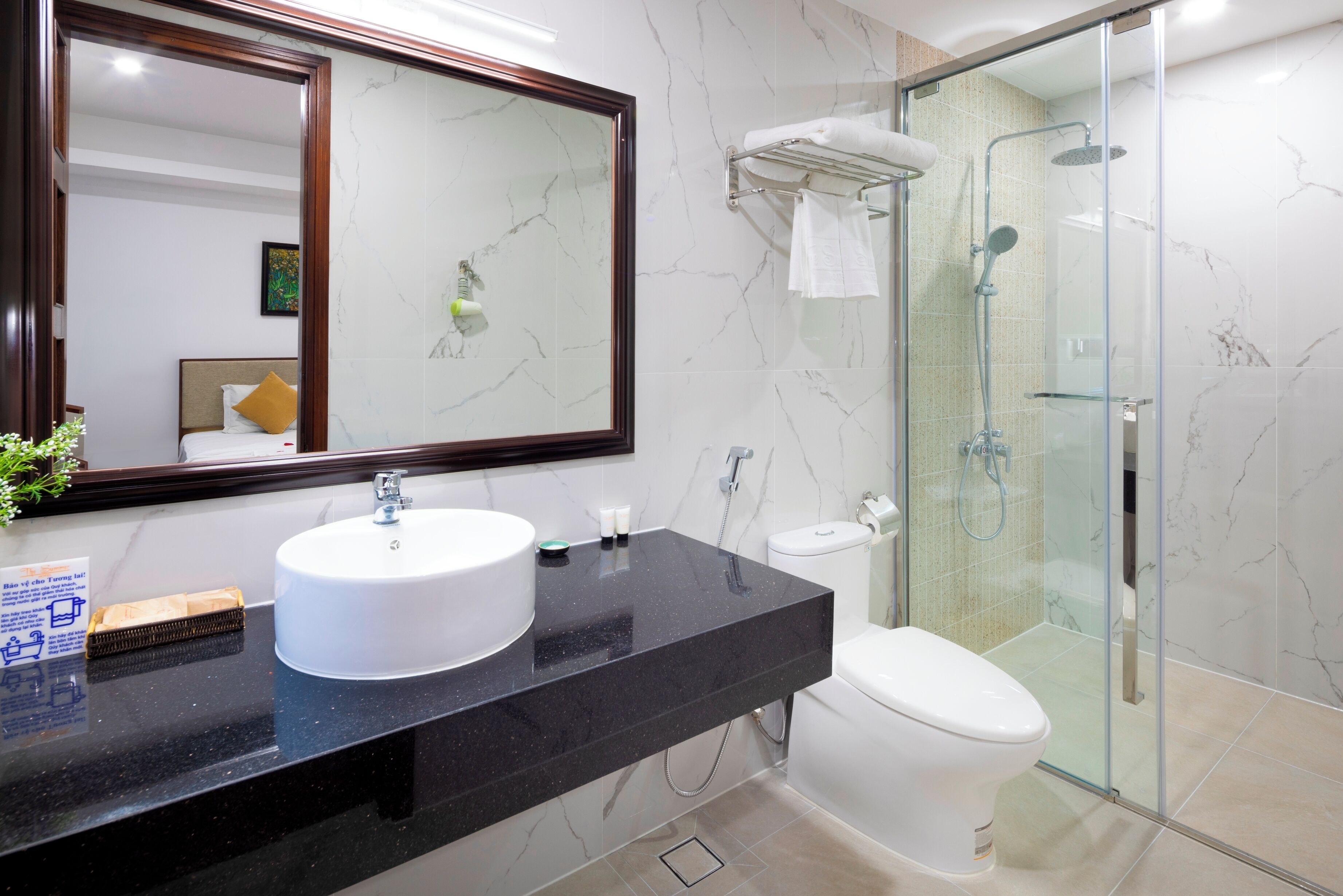 A modern bathroom with a marble sink, toilet, and glass-enclosed shower.