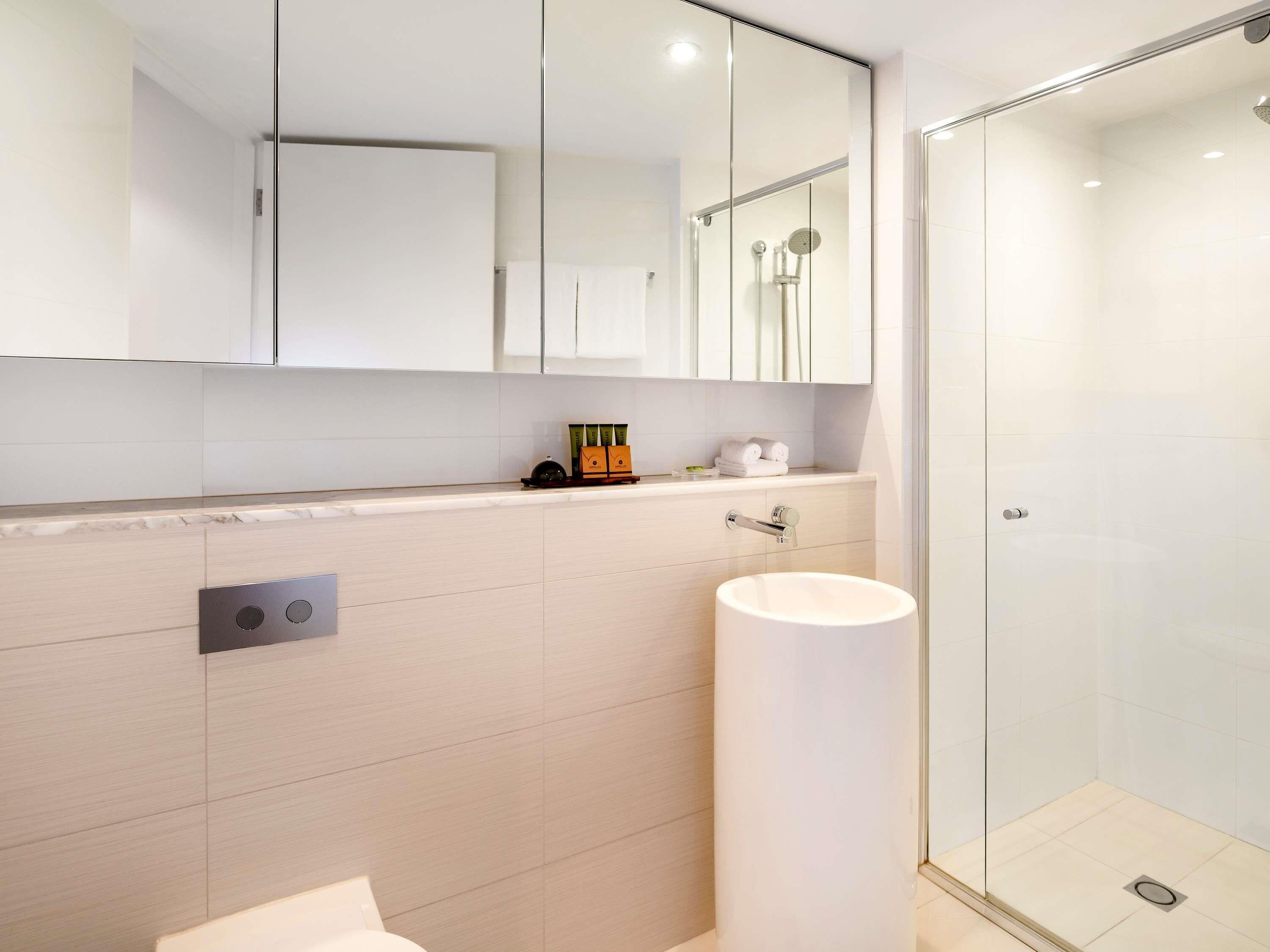 A modern bathroom with a glass shower enclosure, a white sink, and a mirror above the countertop.