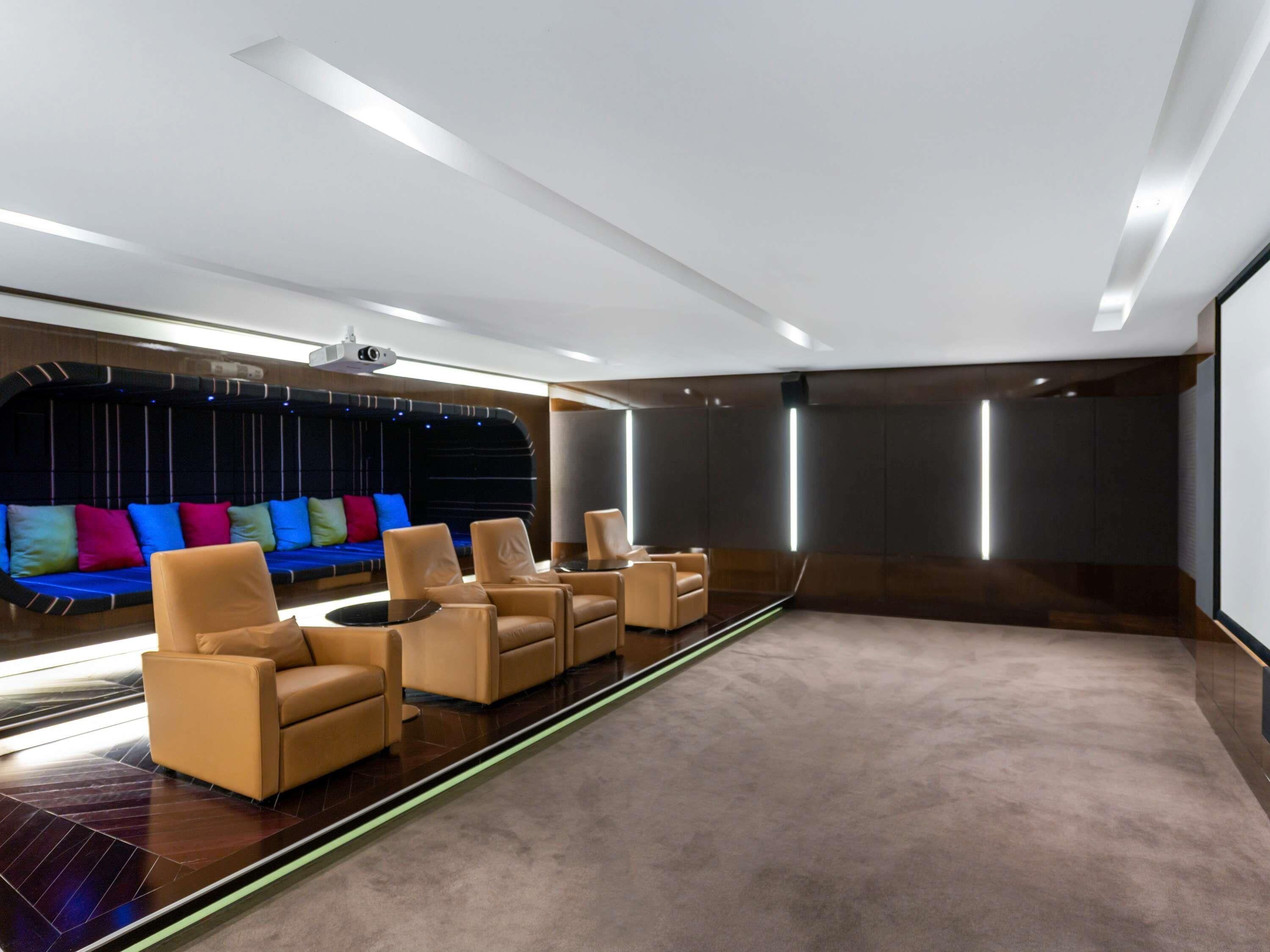 A modern home theater room with a curved seating area, a large screen, and a projector.