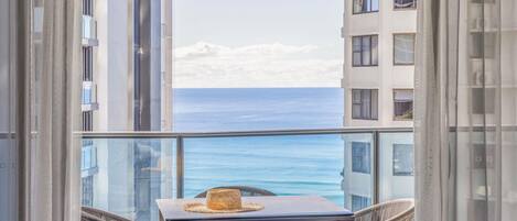 A balcony with a table and chairs, overlooking a body of water and buildings.