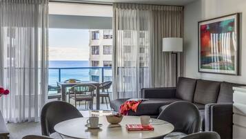 A modern hotel room with a balcony, a round dining table, and a sofa.