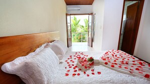 A hotel room with a bed, a wooden headboard, and a view of a balcony with greenery. - Benko's Praia Hotel (Porto Seguro)
