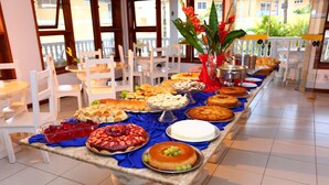 A buffet table with various dishes and a decorative vase. - Benko's Praia Hotel (Porto Seguro)